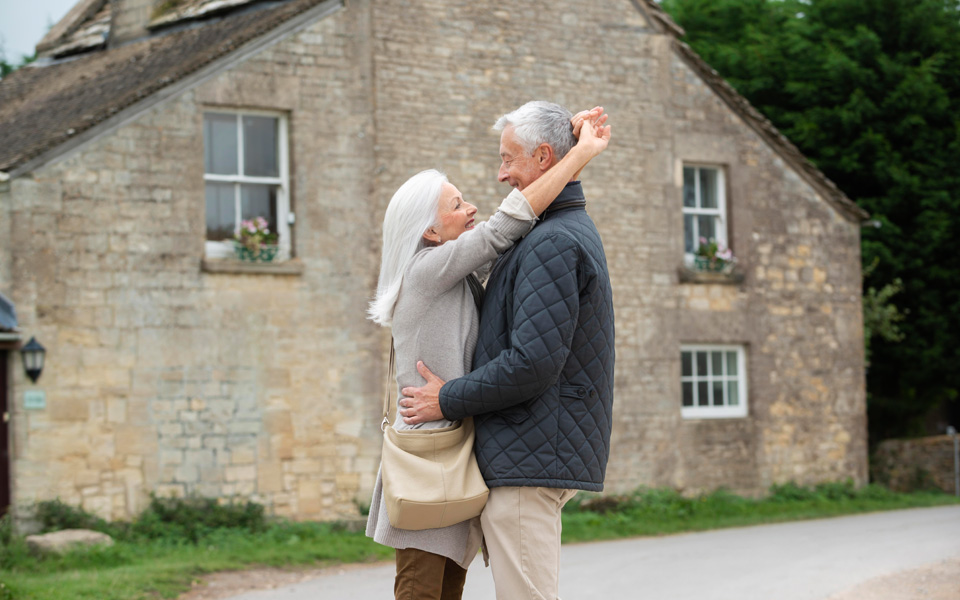 Deux couples seniors heureux devant leur maison