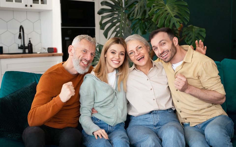 Une famille heureuse avec deux seniors et leurs enfants assis sur un canapé