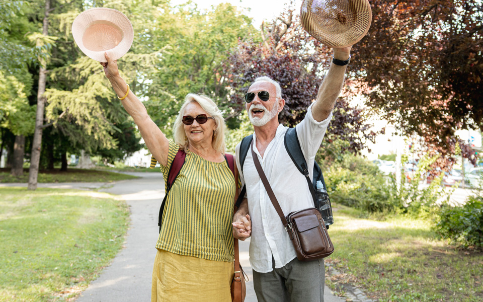 Couple retraité souriant, portant des sacs à dos, prêt pour un voyage