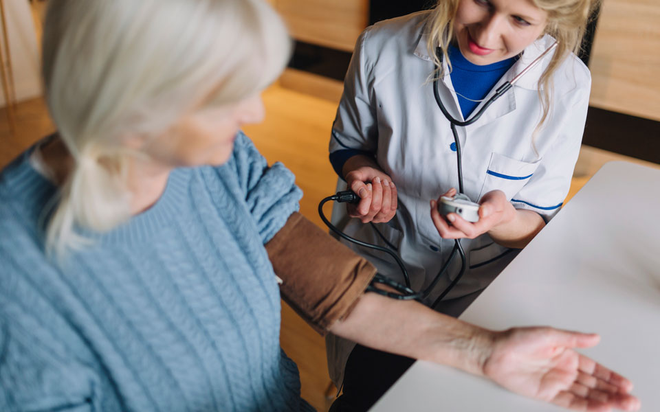 Médecin prenant la tension artérielle d'une femme retraitée lors d'un bilan de santé