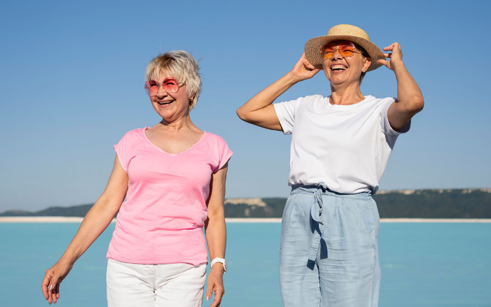 Deux femmes retraitées portant des lunettes de soleil et des chapeaux, souriantes et profitant du plein air