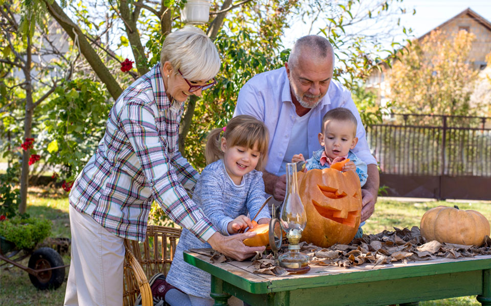 grands-parents heureux sculptant des citrouilles avec leurs petits-enfants en extérieu